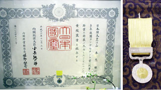 「黄綬褒章」の表彰状（左）と銀製メダル（右）